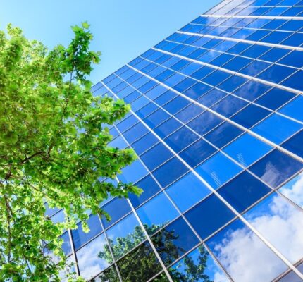 An office building with a tree next to it and a blue sky