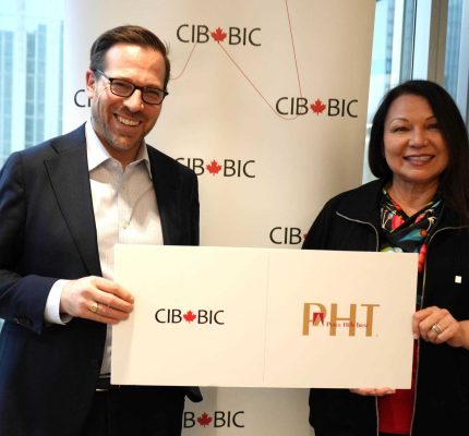 People holding a sign displaying the Canada Infrastructure Bank and Peace Hills Trust logos.