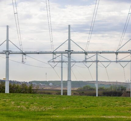Three high voltage transmission towers in green field.