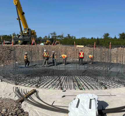 Mise en place de barres d’armature métalliques pour construire la base d’une plateforme d’éolienne.