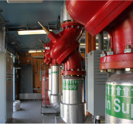 A row of pipes topped with large red valves. A label on the pipes says "Supply"