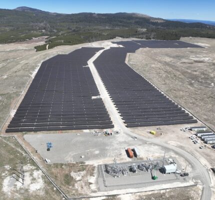 Vue aérienne de panneaux solaires dans un champ ouvert avec des montagnes au loin.
