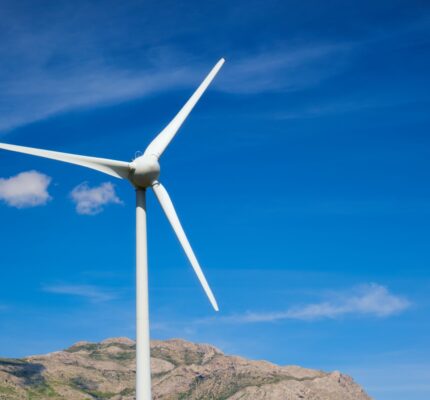Wind turbine generating electricity over a blue sky.