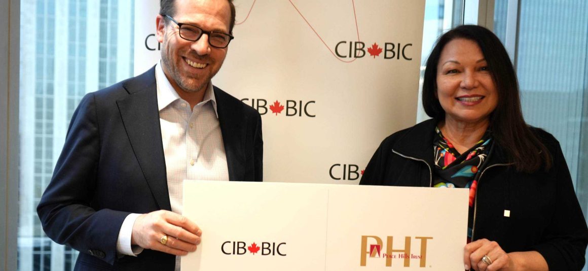 People holding a sign displaying the Canada Infrastructure Bank and Peace Hills Trust logos.