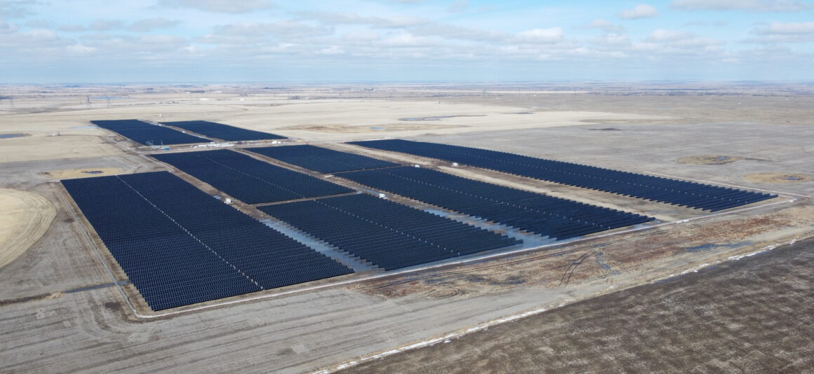 Vue aérienne du parc solaire Duchess avec des rangées de panneaux solaires sur un paysage de prairie.