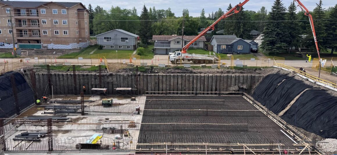 Un chantier de construction où des travailleurs et des machines s'affairent à la construction d'une nouvelle installation de traitement des eaux dans un milieu urbain.
