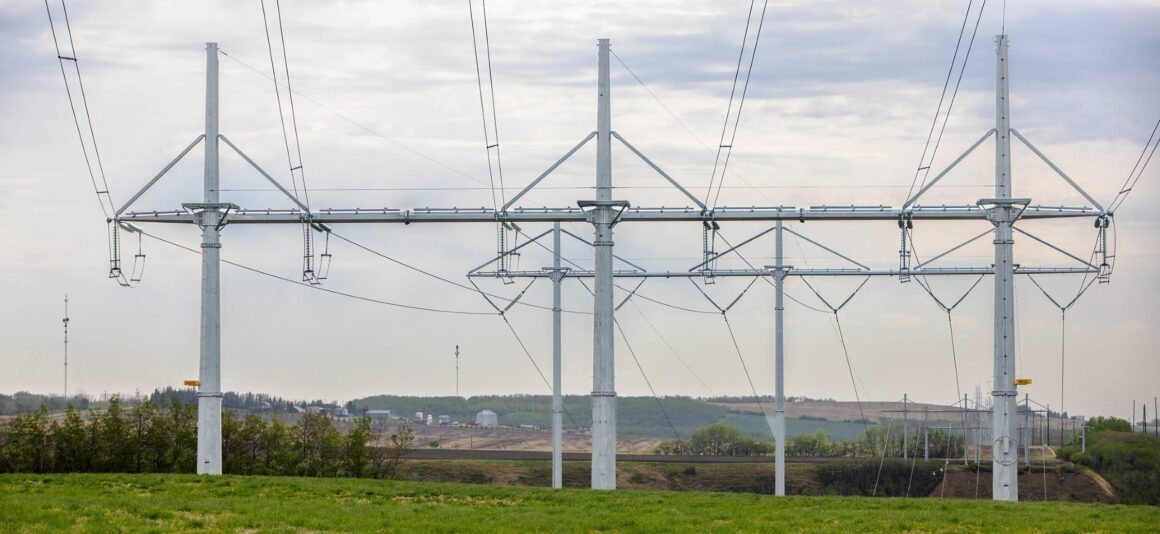 Three high voltage transmission towers in green field.