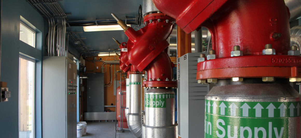A row of pipes topped with large red valves. A label on the pipes says "Supply"