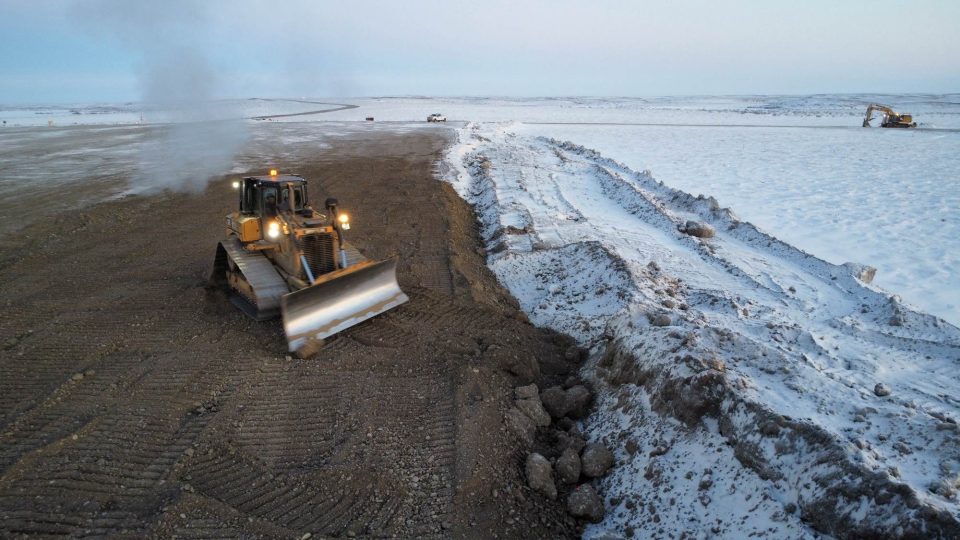 Image of an excavator clearing snow and dirt from the project site