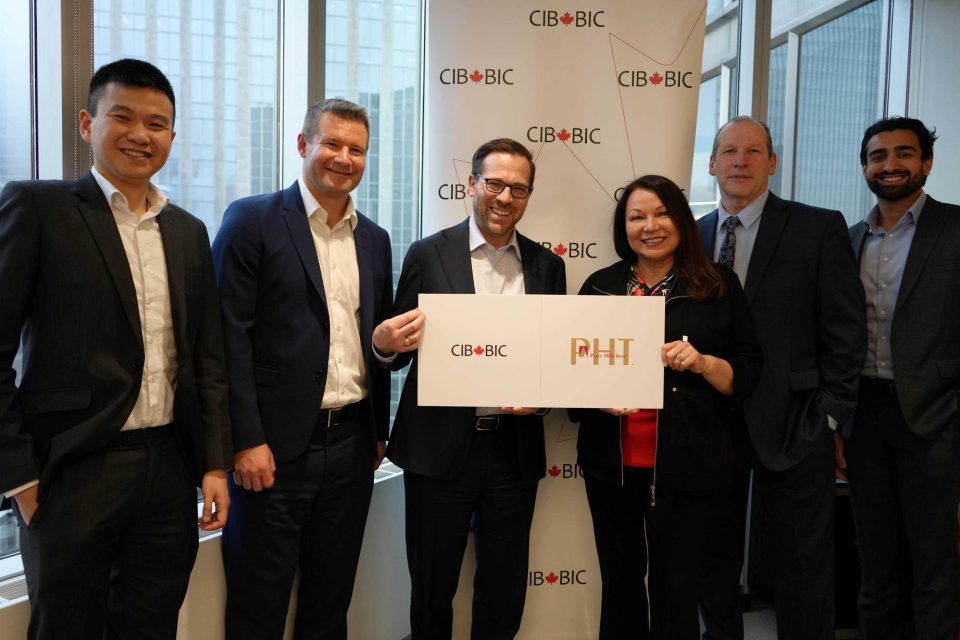 People holding a sign displaying the Canada Infrastructure Bank and Peace Hills Trust logos.