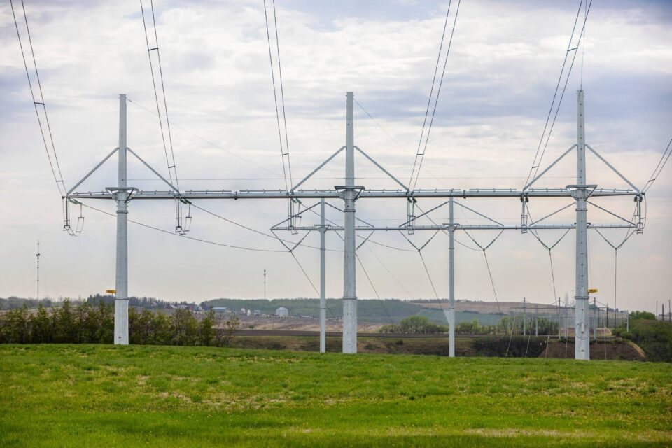 Three high voltage transmission towers in green field.
