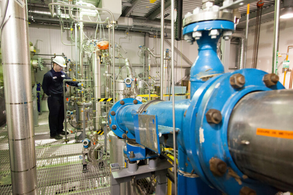 A worker oversees machinery in the ethanol plant in Enerkem Westbury Innovation Center, QC