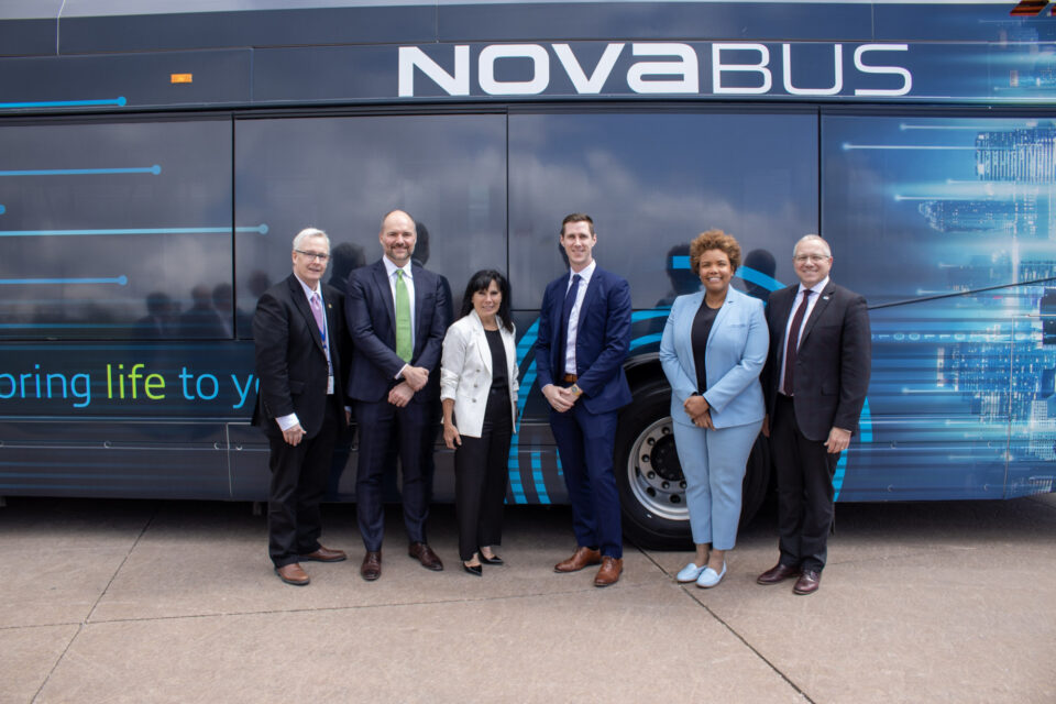 Photo de groupe d’hommes et de femmes devant l’autobus nova