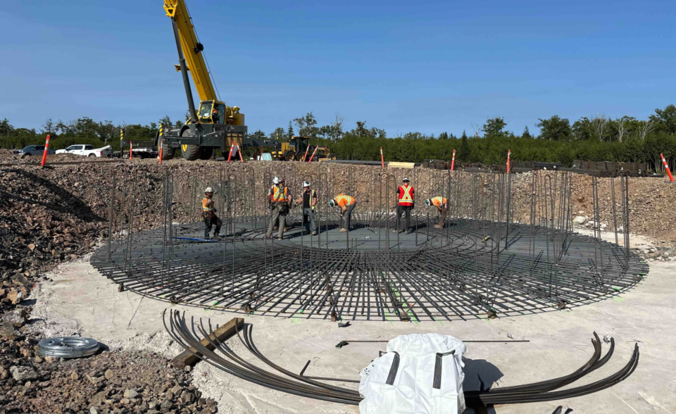 Mise en place de barres d’armature métalliques pour construire la base d’une plateforme d’éolienne.