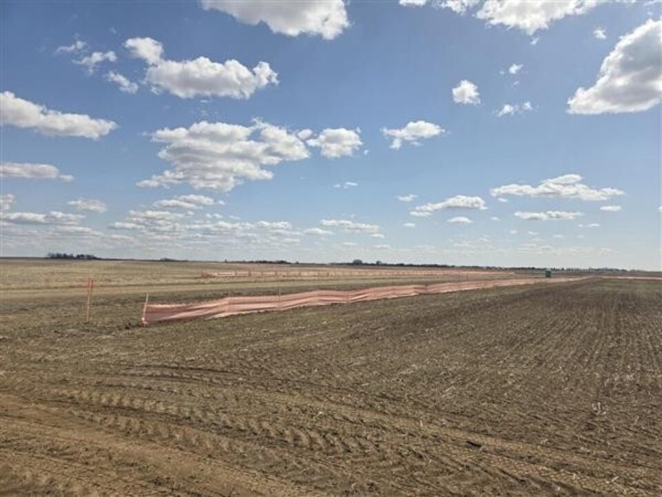 Image of the project site includes an open field that is being cleared for construction.