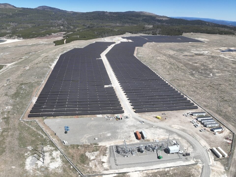 Vue aérienne de panneaux solaires dans un champ ouvert avec des montagnes au loin.