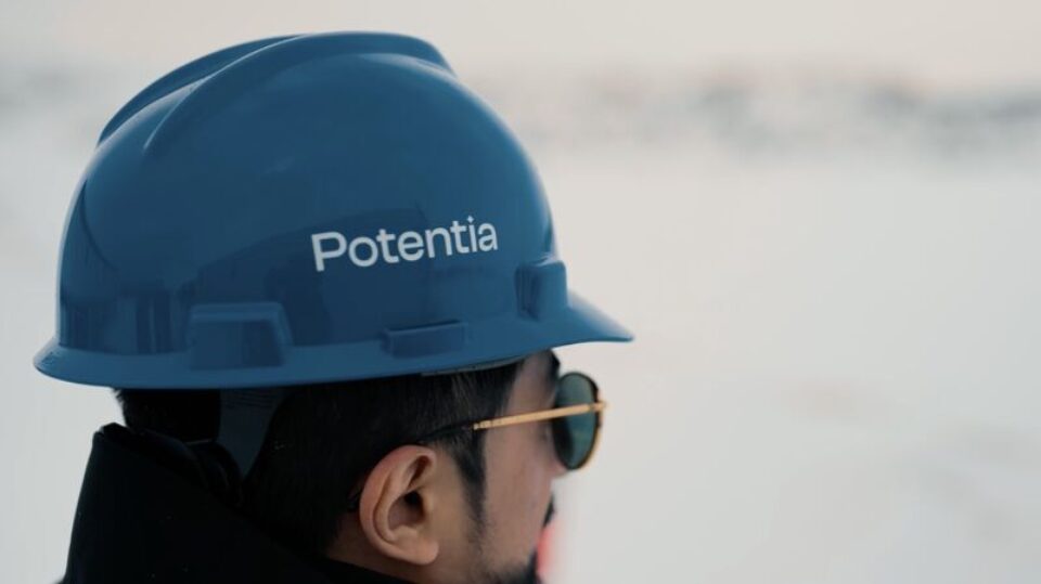 Close-up of a construction worker wearing a blue hard hat labeled “Potentia” and safety glasses.