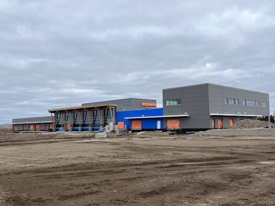 Exterior construction site of the Thompson Airport terminal. Area surrounding the terminal is unpaved.