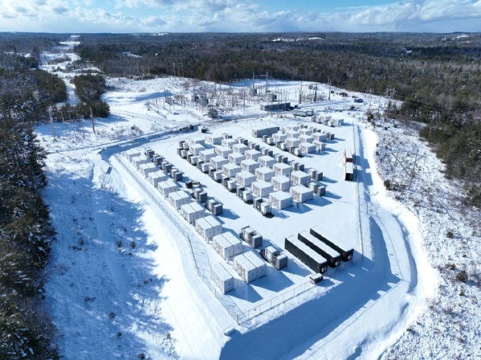 Vue aérienne du site de stockage de batteries achevé à Bridgewater, avec de nombreux conteneurs blancs situés dans une clairière enneigée entourée d’une forêt hivernale sombre.