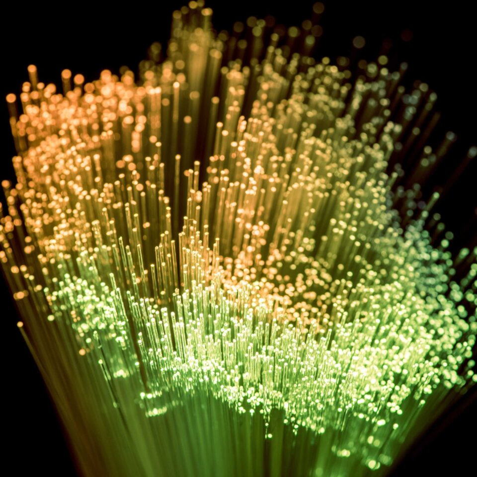 Close-up of many glowing, colorful optical fibers.