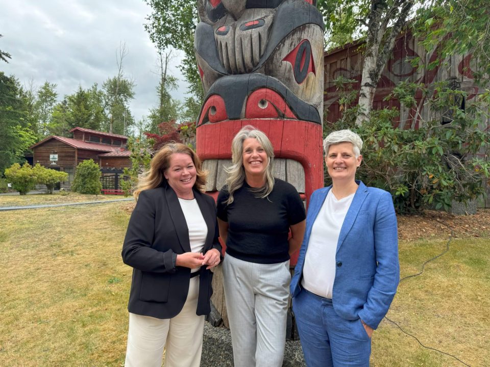 Hillary Thatcher and partners in front of a totem pole