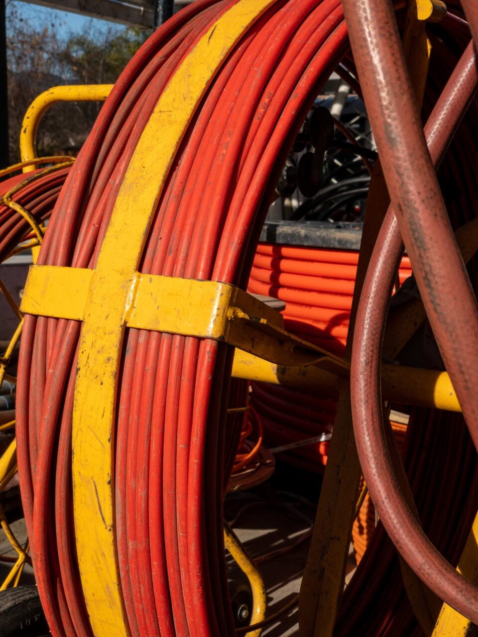 Close-up of a yellow and orange metal reel holding coiled red and orange fibre optic cable.