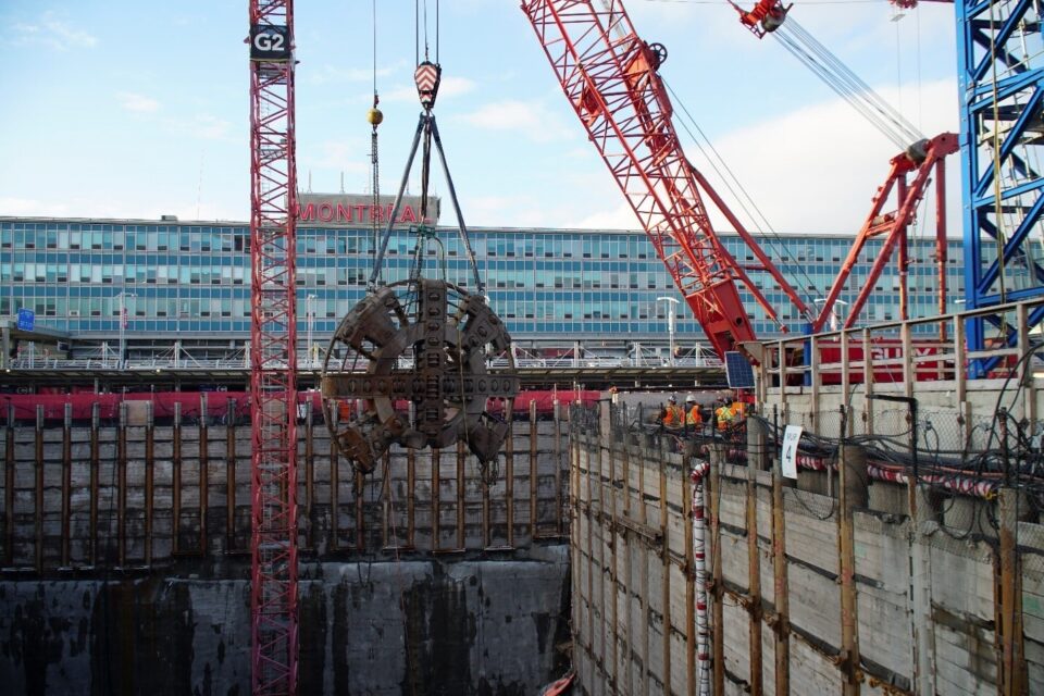 Large cranes enable work crews to operate in a deep open shaft to build the tunnel and station for the REM at Montreal’s Trudeau International Airport.