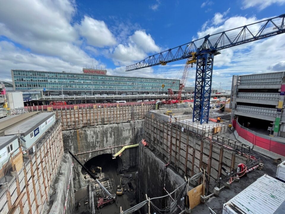 Large cranes enable work crews to operate in a deep open shaft to build the tunnel and station for the REM at Montreal’s Trudeau International Airport.